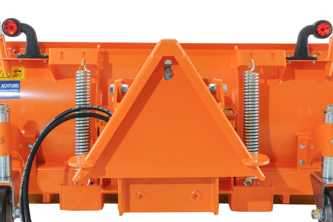 Nahaufnahme eines matev-Schneeräumschilds mit Fokus auf das orangefarbene Kuppeldreieck. Zwei robuste Federn und ein Hydraulikschlauch sind sichtbar, die die Funktionalität und Stabilität unterstützen. Im Hintergrund befinden sich Sicherheitsmarkierungen und reflektierende Elemente. Das Design zeigt die hohe Belastbarkeit und Qualität, ideal für den professionellen Winterdienst.
