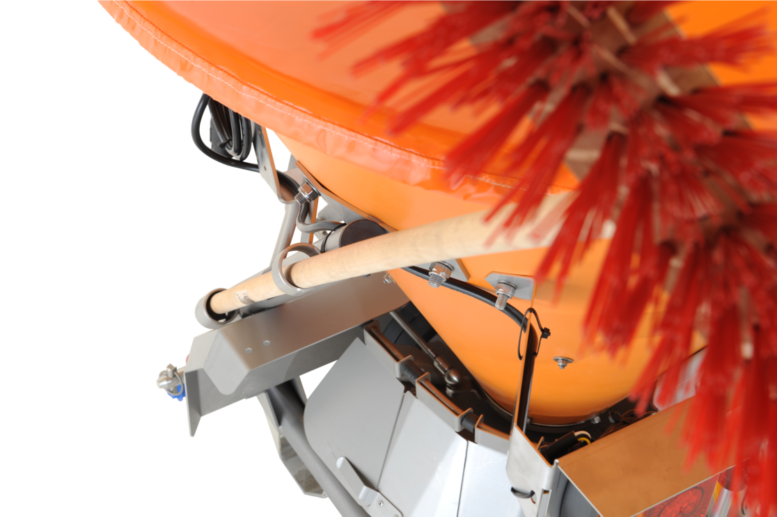 Detaillierte Nahaufnahme eines orangefarbenen matev-Schleuderstreuers mit integriertem Werkzeughalter. Ein Holzstiel ist sicher in der Halterung fixiert. Im Vordergrund sind rote Borsten einer Kehrvorrichtung teilweise sichtbar. Kabel und Befestigungselemente deuten auf eine hochwertige und durchdachte Konstruktion hin, ideal für professionelle Anwendungen in der Flächenpflege.