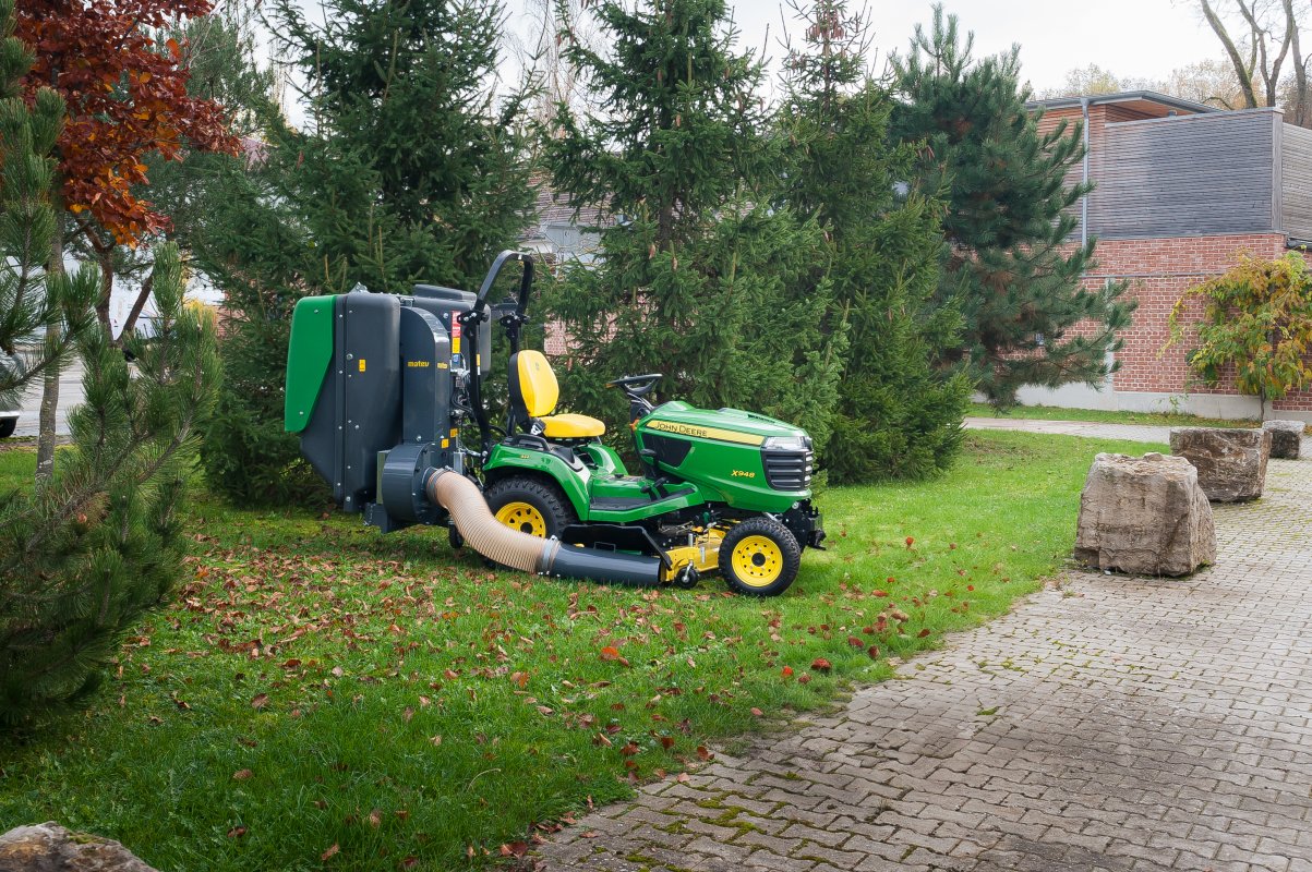 John Deere X948 mit dem Materialaufnahmegerät von matev für Traktoren in der Kommunaltechnik.