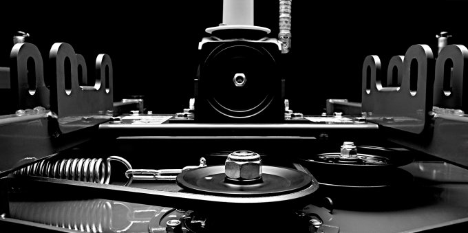 Schwarz-weiß Aufnahme eines technischen Antriebsmechanismus mit sichtbaren Zahnrädern, Federn und Montagedetails, auf schwarzem Hintergrund, der Präzision und Stabilität hervorhebt.